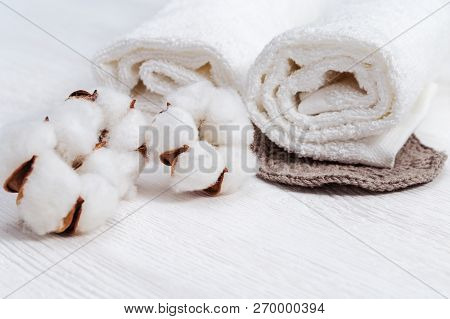 Spa Composition. Two White  Fluffy Towels  And Cotton Flowers On Light Wooden Background With Copy S