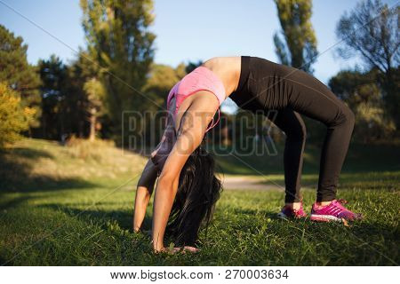 Girl Is Doing Yoga, Standing In Bridge Pose. Setu Bandhasana. With Sunset On Background.