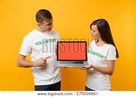 Colleagues Couple In White T-shirt Inscription Volunteer Hold Laptop Pc Computer, Blank Empty Screen
