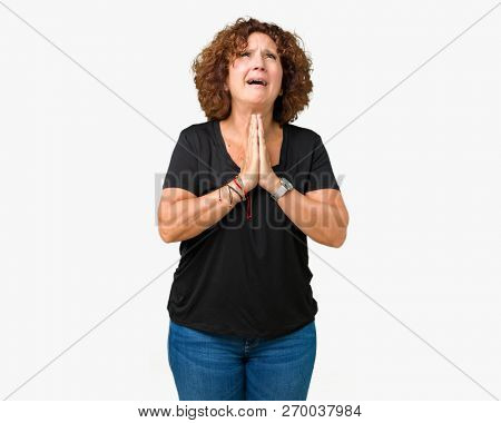 Beautiful middle ager senior woman over isolated background begging and praying with hands together with hope expression on face very emotional and worried. Asking for forgiveness. Religion concept.