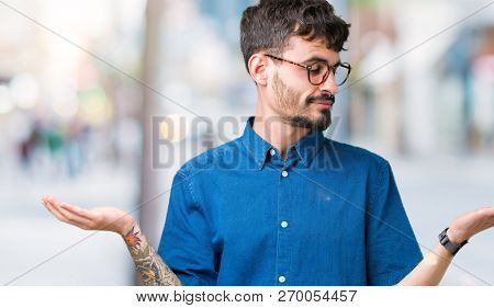 Young handsome man wearing glasses over isolated background Smiling showing both hands open palms, presenting and advertising comparison and balance