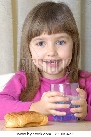 Holčička pít vodu a jíst rohlík.