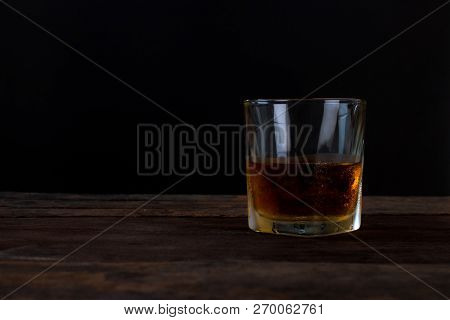 Glass Of Alcohol Scotch Whiskey With Ice On Wooden Table And Black Background