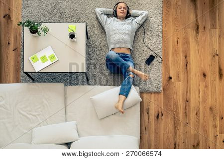 Portrait Of A Young Woman Relaxing And Listening To Music From Smart Phone Using Headphones. Home Of