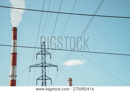 High Red And White Striped Tube Lets Out White Smoke Into Clear Blue Sky. Small Cloud Above Pipe On 