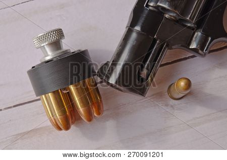 A Loaded Speed Loader Loaded With 38 Special Full Metal Jacket Bullets In Front Of A Black Revolver 