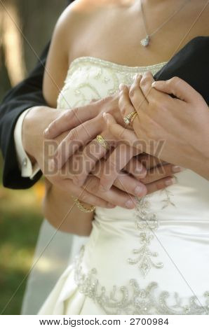 Noiva e noivo mãos sobre vestido de casamento