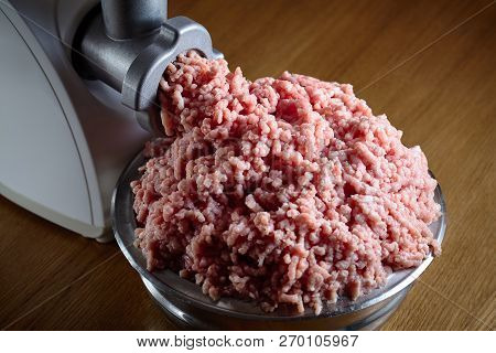Minced Meat Coming Out From Modern Electric Grinder On Oak Table. Healthy Fresh Homemade Minced Meat