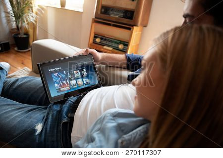 Couple Using Digital Tablet For Watching Movie On Vod Service