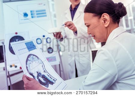 Cheerful Asian Female Staring At Photo Of Head