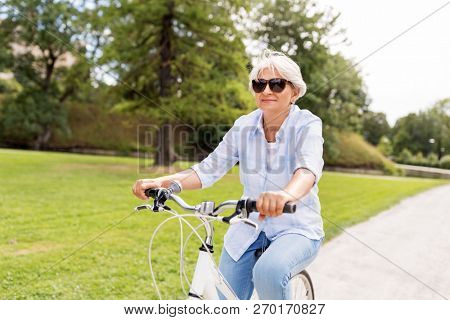 active old age, people and lifestyle concept - happy senior woman riding fixie bicycle at summer park