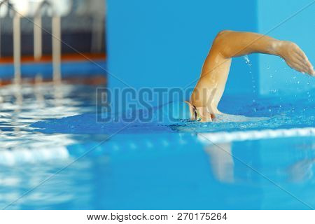 Image of young athlete man in blue cap swimming in pool