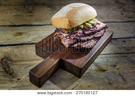 Brisket Sandwich With Cucumber And Coleslow On Cutting Board