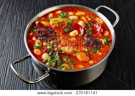 Hearty Fabada Asturiana Bean Stew With Chorizo, Bacon And Blood Sausages In A Metal Casserole On A B