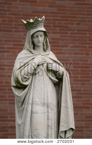 Estátua de anjo em frente a parede de tijolo