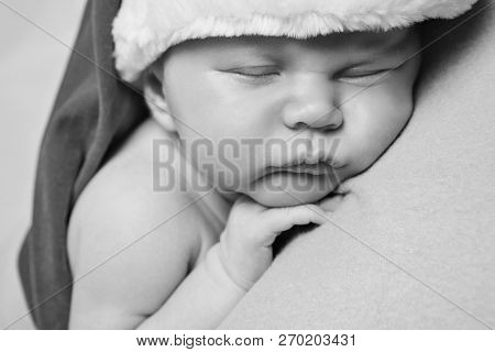 A Naked Newborn Baby Sleeps In A Christmas Hat.