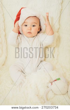 A Naked Baby Plays In A Christmas Hat.