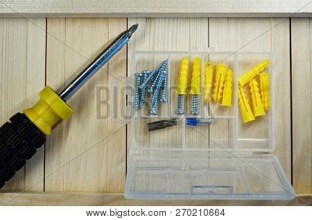Screws, Dowels And Screwdriver Lie On The Boards. Box-organizer For The Carpenter. Locksmith Work Wi