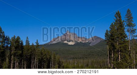 Photograph Of Mount Thielsen On A Sunny Clear Day With Vivid Blue Skies And Green Forest