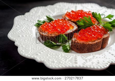 Red Caviar On Black Bread With Butter. Healthy Food. Fish Appetizer. Dark Background