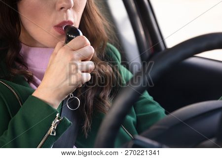 Side View Of A Beautiful Young Woman Sitting Inside Car Taking Alcohol Test
