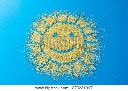 Cute Background. Confectionery Sprinkles Shape Of The Sun With A Smile. Yellow Sugar Grains On A Blu