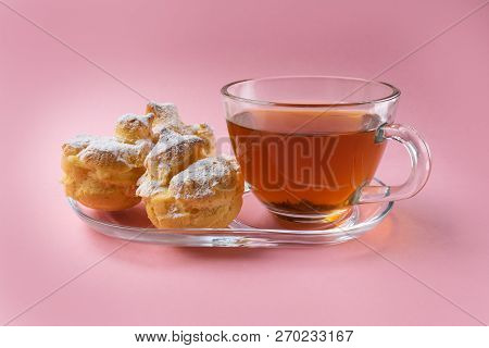 A Cup Of Green Tea And Three Profiteroles Sprinkled With Sugar Powder On A Pink Background. Stock Im