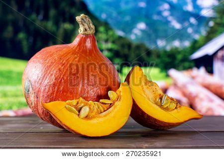 Group Of One Whole Two Slices Of Fresh Red Kuri Pumpkin Hokkaido Variety With Country Nature In Back