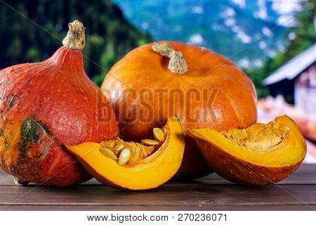 Group Of Two Whole Two Slices Of Fresh Red Kuri Pumpkin Hokkaido Variety With Country Nature In Back