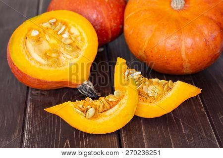 Group Of Two Whole One Half Two Slices Of Fresh Red Kuri Pumpkin Hokkaido Variety On Brown Wood