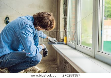 Man In A Blue Shirt Does Window Installation