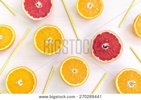 Orange And Grapefruit Slices Lying On Alight Background With Juice Straws Among Them.