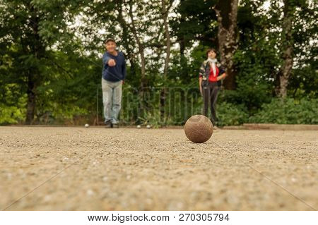 Couple Man And Woman Play Petanque On Fine Stone Field.
