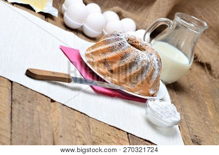 Homemade Bundt Cake Sprinkled With Sugar, Milk And Eggs In Background
