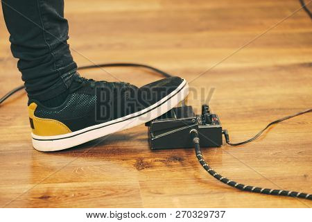 Man With Musical Instrument Setting Up Guitar Audio Stomp Box Effects And Cables In Music Studio
