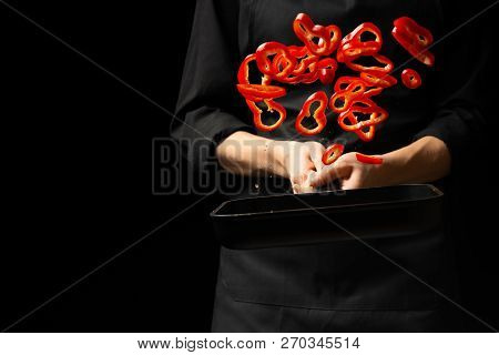 Professional Cook. Chef Preparing Dish With Red Sweet Pepper In A Pan, Paprika. On A Black Backgroun