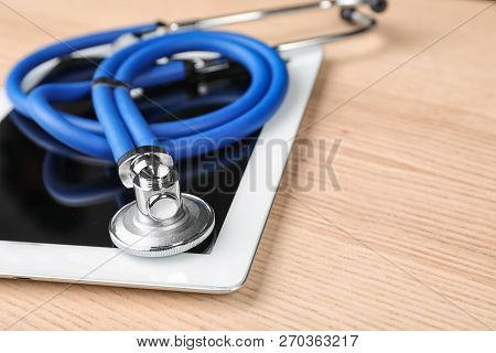 Stethoscope For Checking Pulse And Tablet On Wooden Table, Closeup. Space For Text