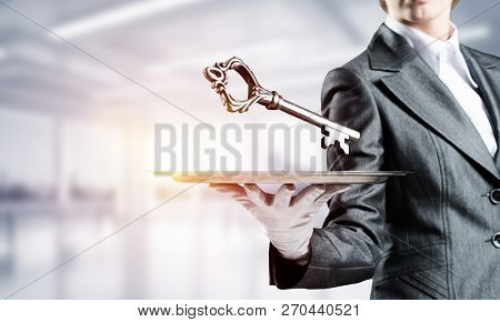 Cropped Image Of Waitresss Hand In White Glove Presenting Big Key On Metal Tray With Office View On 