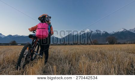 One Caucasian Children Walk With Bike In Wheat Field. Little Girl Walking Black Orange Cycle On Back