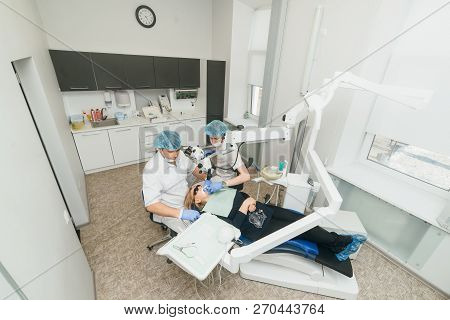Doctor Used Microscope. Dentist Is Treating Patient In Modern Dental Office. Operation Is Carried Ou