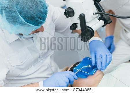 Doctor Used Microscope. Dentist Is Treating Patient In Modern Dental Office. Operation Is Carried Ou