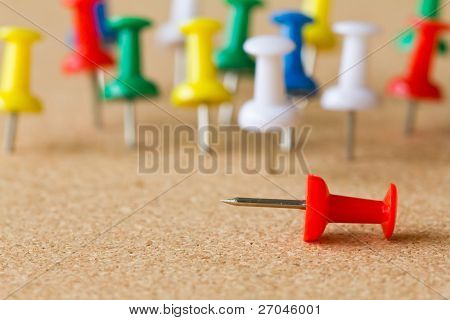 Gruppo di colorati push pin sulla bacheca di sughero.