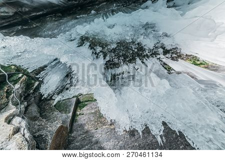 Winter Baikal. Olkhon Island. Ice Grotto. Thick Blue Ice And Icicles On The Coastal Rocks Of Olkhon 