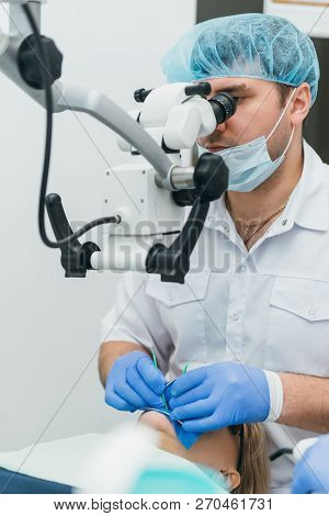 Doctor Used Microscope. Dentist Is Treating Patient In Modern Dental Office. Operation Is Carried Ou