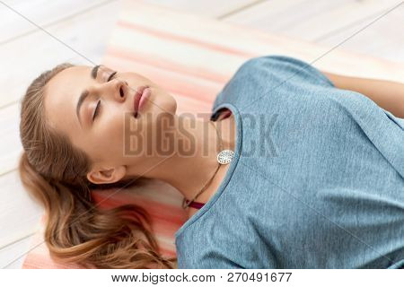 fitness, sport and healthy lifestyle concept - woman doing yoga corpse pose at studio
