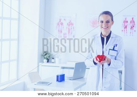 A doctor with stethoscope examining red heart, isolated on white background