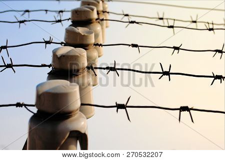 Barbed Wire With Electricity Against The Sky With A Ceramic Insulator