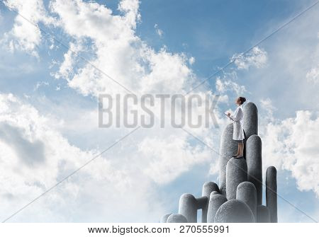 Young Female Doctor With Folder In Hands Satnding On Stone Column