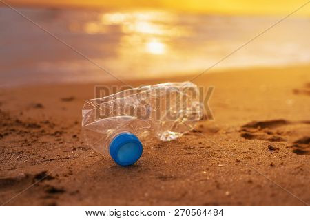 The Plastic Bottle  On The Beach At The Sunset