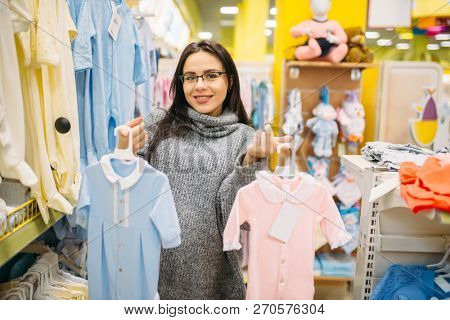 Woman choosing clothes in the store for newborns